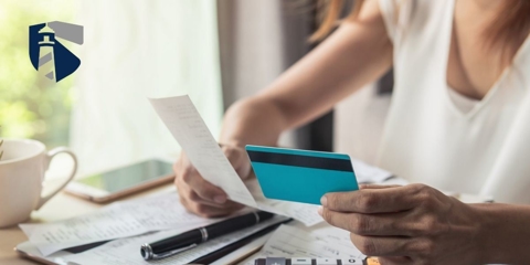 Woman holds credit card in one hand and reviews a bill in the other